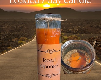 May include: A tall orange candle in a clear glass cylinder with a tan label reading Road Opener and Miss Katt's Emporium. The top view shows the orange wax surface covered with dried herbs and a single centered wick, tied with twine.