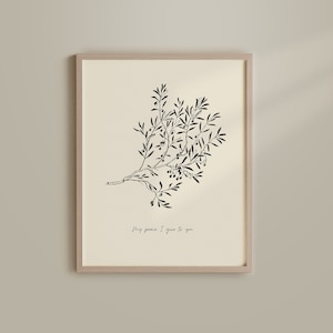 Op de afbeelding: Een ingelijste print met een zwart-wit illustratie van een olijftak met bladeren en olijven. De tekst "My peace I give to you" staat eronder. De lijst heeft een lichte houtkleur.