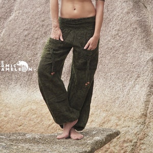 Puede incluir: Una mujer con un top halter color óxido y pantalones cargo verde oliva con bolsillos. Los pantalones tienen un corte holgado. El logo de Karmic Chameleon es visible. La mujer está de pie sobre una roca.