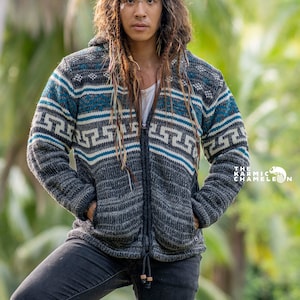 Op de afbeelding: Een persoon draagt een grijze hoodie met blauwe en witte strepen en een geometrisch patroon. De trui heeft een ritssluiting en is gemaakt van een zachte, comfortabele stof.