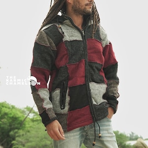May include: A patchwork zip-up hoodie in shades of grey, black, and burgundy. The jacket features a drawstring hood and a front pocket. The Karmic Chameleon logo is visible in the image. The person is wearing light blue jeans.