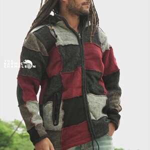 May include: A patchwork zip-up hoodie in shades of gray, black, and burgundy. The jacket features a hood, a drawstring, and a front zipper. The Karmic Chameleon logo is visible on the left side of the jacket.