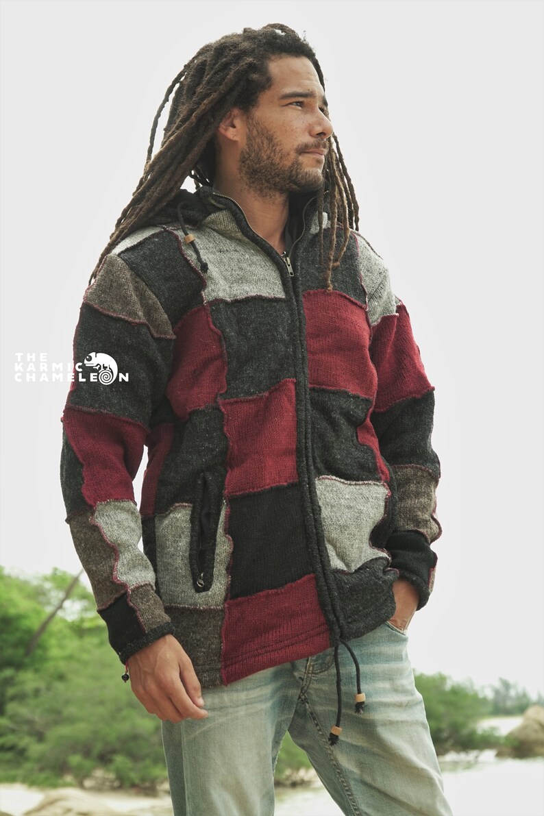 May include: A patchwork zip-up hoodie in shades of gray, black, and burgundy. The jacket features a hood, a drawstring, and a front zipper. The Karmic Chameleon logo is visible on the left side of the jacket.