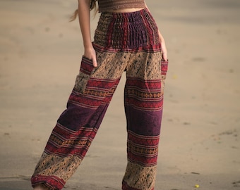 Puede incluir: Un top halter de encaje marrón combinado con pantalones holgados de cintura alta con pretina fruncida y bolsillos laterales. Los pantalones muestran un patrón multicolor en tonos rojo oscuro, morado y beige con motivos geométricos.