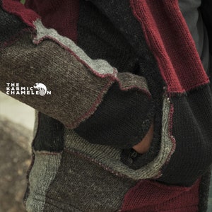 May include: A patchwork knit jacket in shades of gray, black, and burgundy. The jacket features a variety of textured knit panels, with visible seams and a zipper. The Karmic Chameleon logo is visible on the left side.