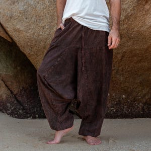 Op de afbeelding: Bruine harembroek met een trekkoord in de taille en zakken. De broek heeft een relaxte pasvorm en is gemaakt van een textuurstof. Het model draagt een wit t-shirt. De broek is ongeveer 102 cm lang.