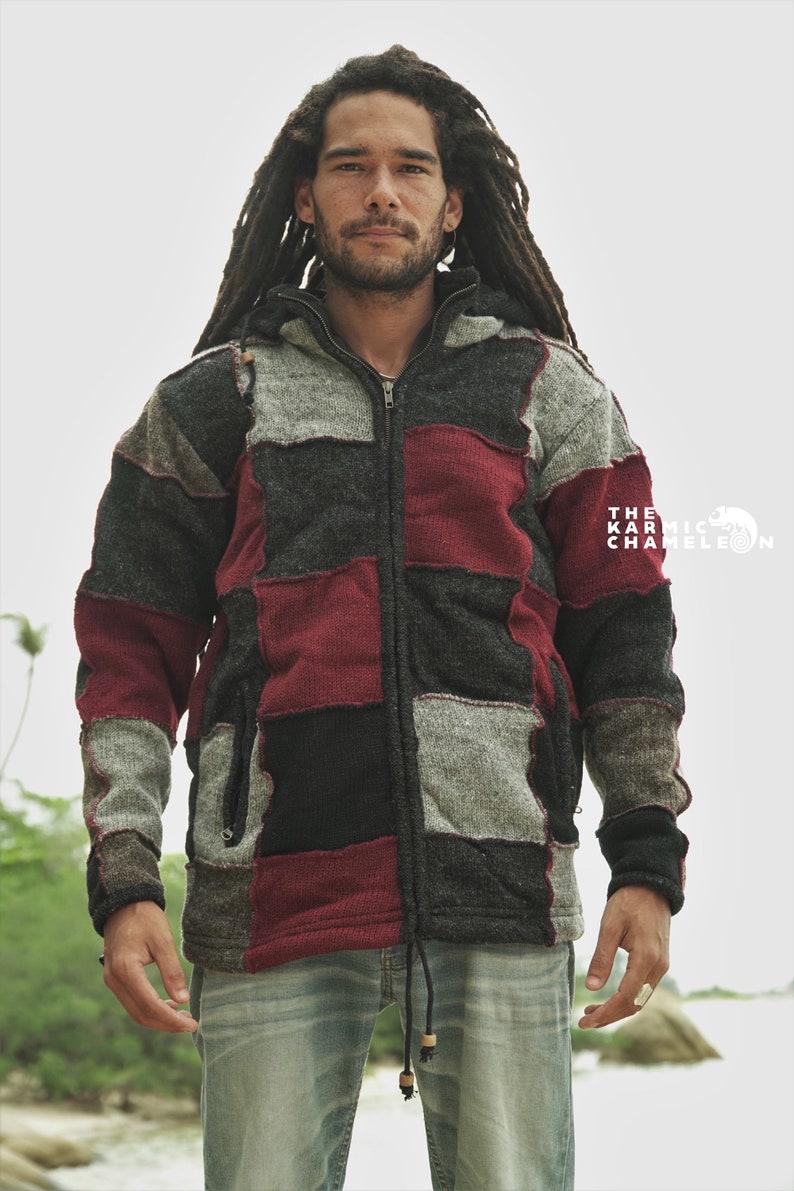 May include: A patchwork zip-up hoodie in shades of gray, black, and burgundy. The jacket features a hood, a front zipper, and a drawstring at the hem. The Karmic Chameleon logo is visible on the right side.