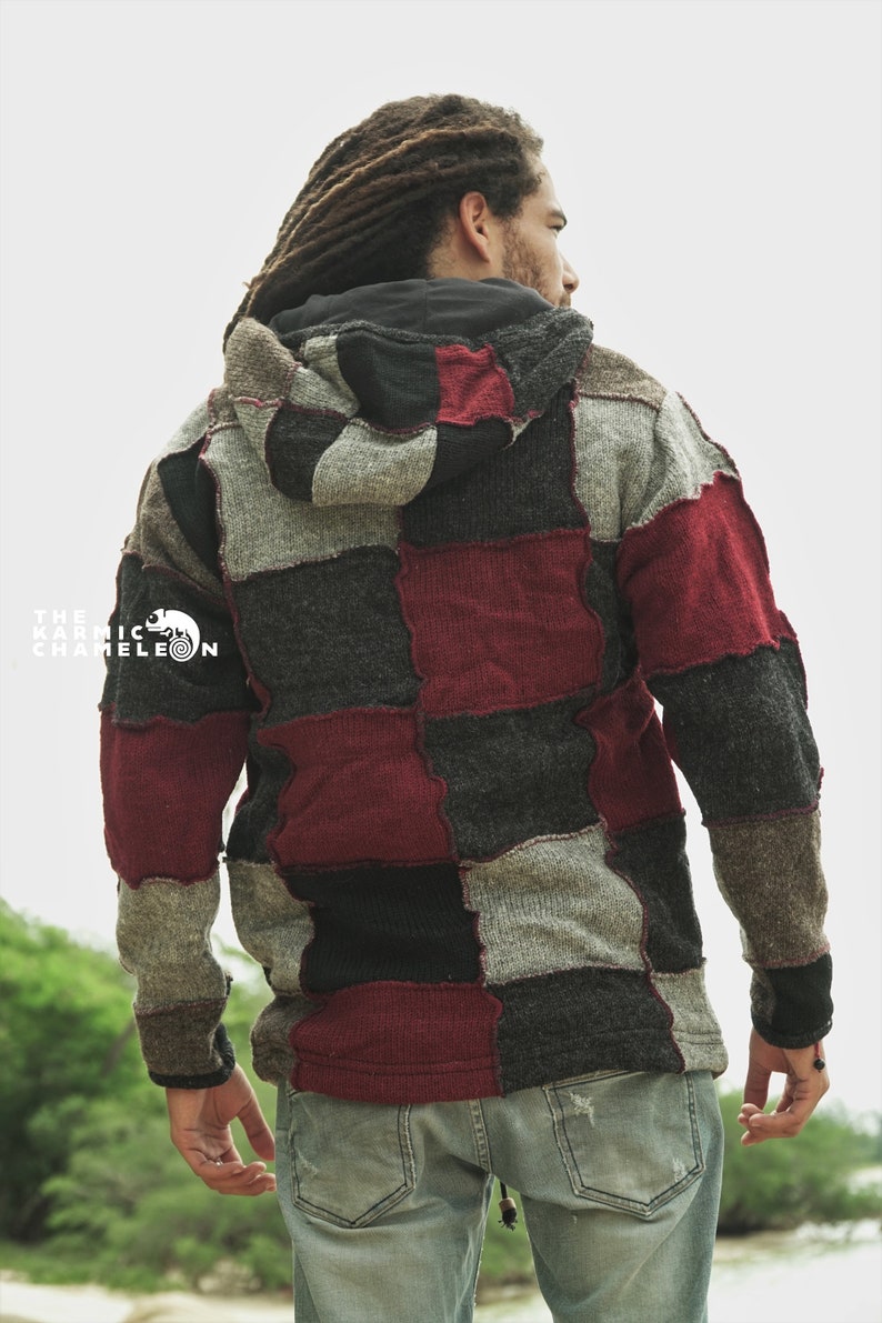 May include: A patchwork hoodie in shades of gray, black, and burgundy. The hoodie features a hood and is worn with light blue jeans. The Karmic Chameleon logo is visible on the left side of the hoodie.