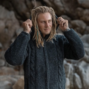Man pulling up the hood on this chunky grey Aran knit hoodie - perfect for winter gardening or dog walking