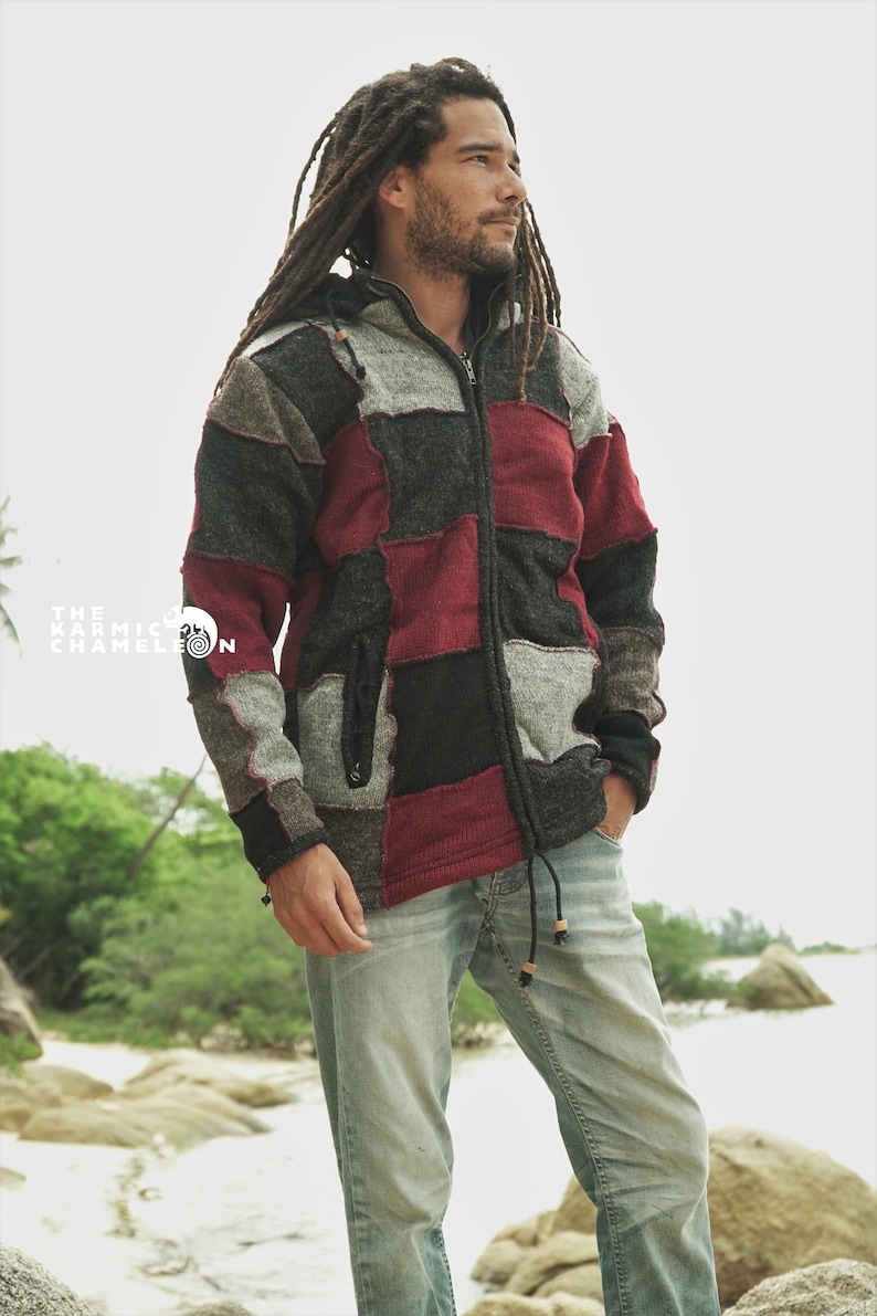 May include: A patchwork zip-up hoodie in shades of gray, black, and burgundy. The jacket features a drawstring hood and a front pocket. The Karmic Chameleon logo is visible in the image. The person is wearing light blue jeans.