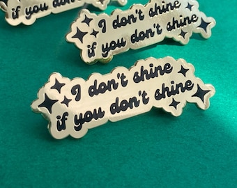 May include: Three gold-colored enamel pins with a black outline and text that reads "I don't shine if you don't shine".