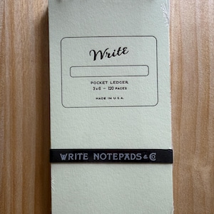 May include: A light green pocket ledger notepad with a black spiral binding. The cover features the text Write, Pocket Ledger, 3x6 - 120 pages, and Made in U.S.A. A black horizontal band across the bottom displays the text Write Notepads & Co.