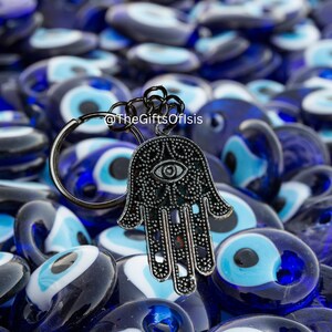 May include: A silver Hamsa hand charm keychain with a blue evil eye in the center, surrounded by many blue evil eye beads.