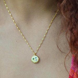 May include: A gold chain necklace with a round pendant featuring a cluster of colourful gemstones. The pendant has a star, a heart, and two other gemstones.