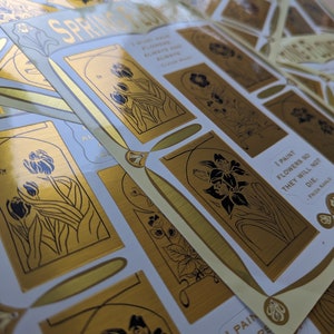 May include: Gold foil stickers with black line drawings of flowers and the quote "I paint flowers so they will not die." by Frida Kahlo.