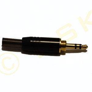 May include: A black and gold audio connector with a spring-loaded strain relief. The connector has a gold-plated tip and a black plastic housing.