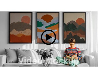 May include: Three framed abstract landscape art prints with a sunset theme. The artwork features warm colors like orange, brown, and green. A person is sitting on a gray sofa, reading a book.