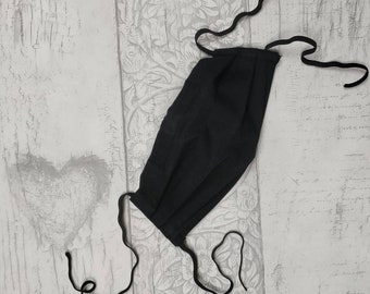 Face mask in 3 layers of black cotton. Hand made and adjustable, reusable and washable. Tie behind ears or behind head. Strings or loops.