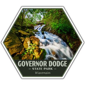 May include: Hexagon-shaped sticker featuring a scenic waterfall in Governor Dodge State Park, Wisconsin. The image shows a cascading waterfall over rocks, with a wooden bridge and lush greenery. The text "GOVERNOR DODGE - STATE PARK - Wisconsin" is at the bottom.