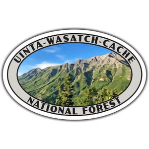 May include: Oval sticker featuring a scenic mountain landscape under a blue sky. The sticker reads "UINTA-WASATCH-CACHE NATIONAL FOREST" in a circular design around the image of the mountains.