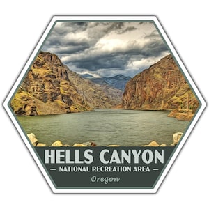 May include: A hexagonal sticker featuring a scenic view of Hells Canyon National Recreation Area in Oregon. The image shows a river winding through a canyon with rocky cliffs under a cloudy sky. The text "HELLS CANYON - NATIONAL RECREATION AREA - Oregon" is at the bottom.