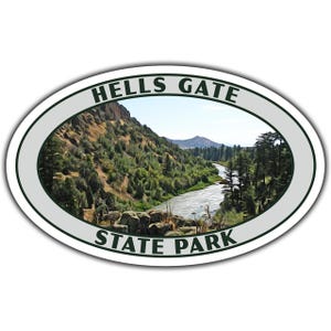 May include: Oval sticker featuring a scenic landscape of Hells Gate State Park. The image depicts a river winding through a valley with lush green trees and mountains under a blue sky. The text "HELLS GATE STATE PARK" is displayed.