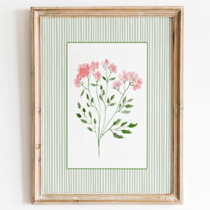 May include: A framed wall art print featuring a watercolour illustration of pink flowers with green leaves. The artwork is centred on a white background with a light green and white vertical striped border, all enclosed in a light wood frame.