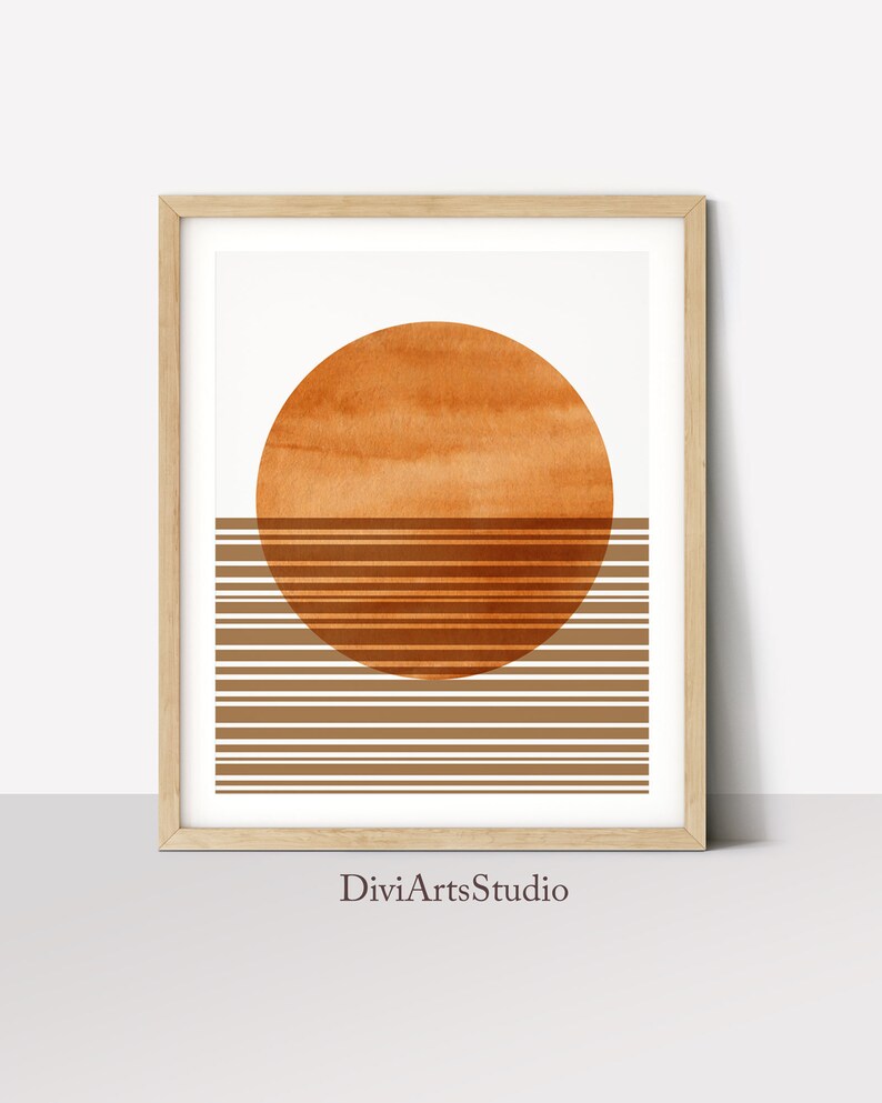 Pu&ograve; includere: Stampa d'arte astratta con un grande cerchio arancione e strisce orizzontali marroni. La stampa &egrave; incorniciata in una cornice di legno chiaro e ha il testo "DiviArtsStudio" in basso.