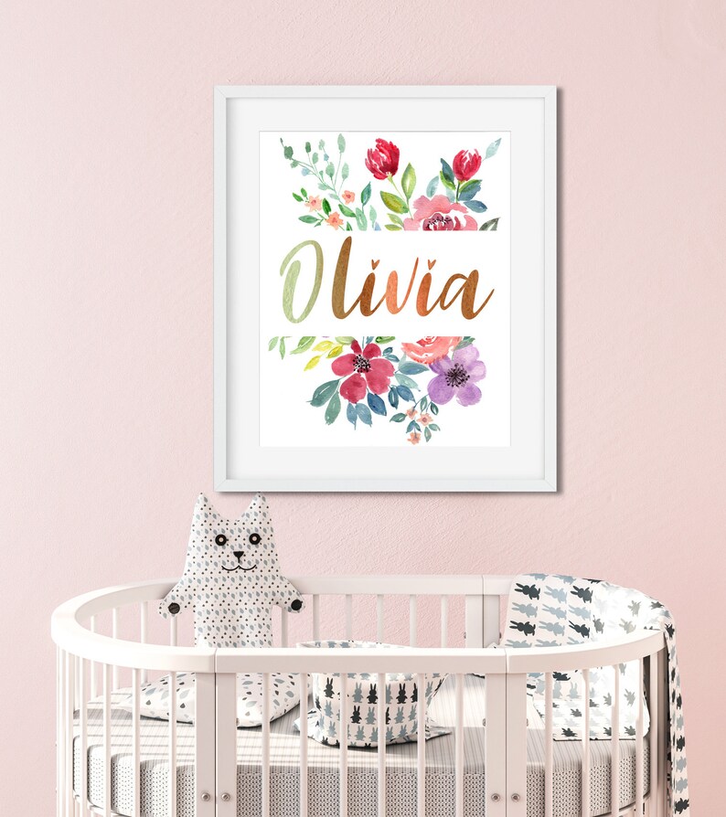 Pu&ograve; includere: Una stampa incorniciata bianca con un design floreale ad acquerello e il nome "Olivia" in lettere dorate.