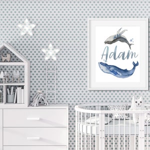 May include: A white framed print with a watercolor illustration of two whales, one blue and one gray, with the name "Adam" written in silver script.