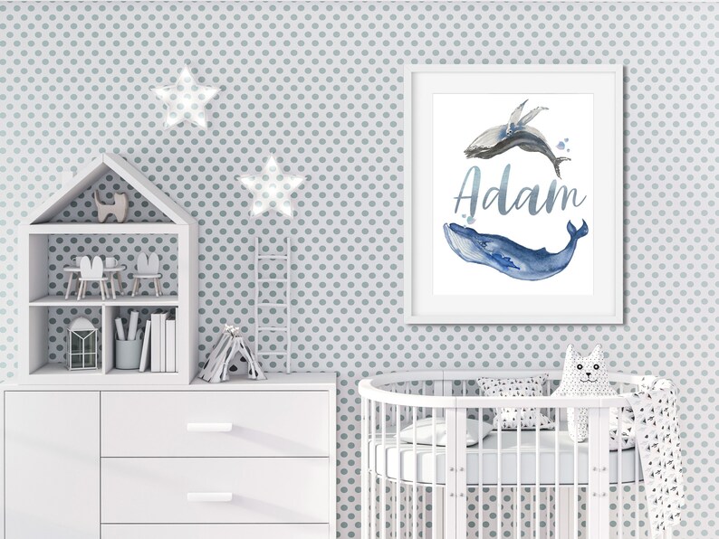 May include: A white framed print with a watercolor illustration of two whales, one blue and one gray, with the name "Adam" written in silver script.