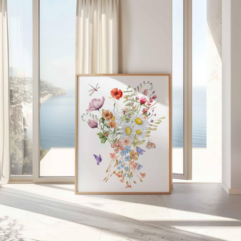 以下が含まれることがあります： ピンク、白、オレンジ、ブルーの色合いの花束を描いた水彩画。花は花瓶に活けられ、緑の葉で囲まれています。絵には、蝶が2匹とトンボも描かれています。