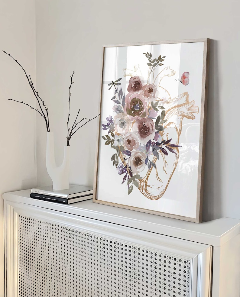 K&ouml;nnte beinhalten: Ein gerahmter Druck eines anatomischen Herzens in Aquarell mit rosa, lila und wei&szlig;en Blumen und Gr&uuml;n. Das Herz ist in Gold umrandet.