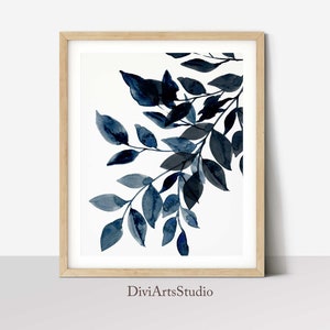 May include: A framed watercolor painting of a branch with blue leaves on a white background. The painting is signed "DiviArtsStudio" in the bottom center.