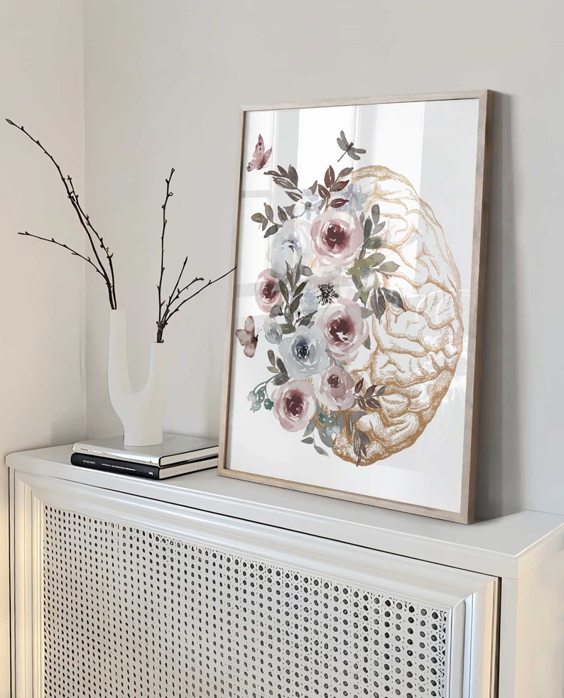 K&ouml;nnte beinhalten: Ein gerahmter Druck eines goldenen anatomischen Gehirns mit Aquarellblumen in Rosa-, Blau- und Gr&uuml;nt&ouml;nen. Die Blumen sind um das Gehirn herum angeordnet und bilden ein wundersch&ouml;nes und einzigartiges Design.