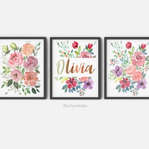 Pu&ograve; includere: Tre stampe ad acquerello con bouquet di fiori in tonalit&agrave; rosa, viola e verde. La stampa centrale ha il nome "Olivia" scritto in corsivo dorato.