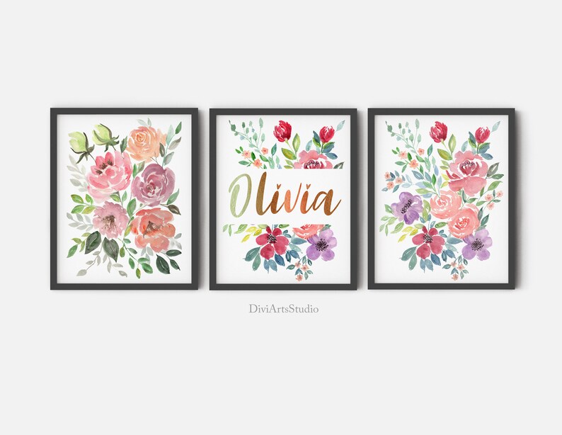 Pu&ograve; includere: Tre stampe ad acquerello con bouquet di fiori in tonalit&agrave; rosa, viola e verde. La stampa centrale ha il nome "Olivia" scritto in corsivo dorato.