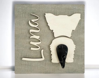 May include: A wooden sign with a white silhouette of a dog's rear end and a black hook. The name "Luna" is written in cursive on the sign.