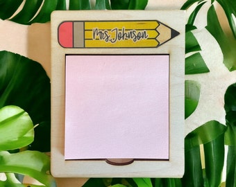 May include: A wooden pencil-shaped note holder with a pink sticky note and the text "Mrs. Johnson" on the pencil.
