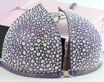 Può includere: Un top di bikini viola con strass iridescenti. Il top è realizzato in tessuto elastico e ha un cinturino stile halter.