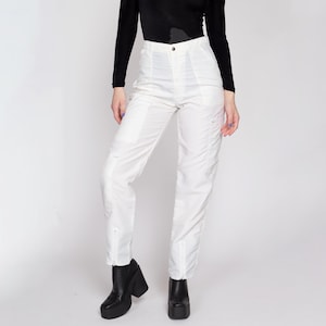 May include: White cargo trousers with a zip detail on the legs. The trousers have a high waist and are made from a lightweight fabric.