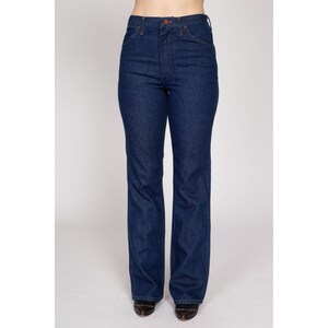 K&ouml;nnte beinhalten: Dunkelblaue Jeans mit hoher Taille und klassischem F&uuml;nf-Taschen-Design. Die Jeans haben einen geraden Beinverlauf und einen Knopf- und Rei&szlig;verschluss. Die Jeans sind einfarbig und scheinen aus strapazierf&auml;higem Denim-Material zu sein.