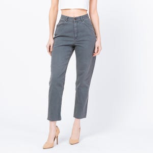 May include: Gray denim jeans with a high waist and straight leg. The jeans have a button and zipper closure, and classic five-pocket styling. The model is wearing nude-colored high heels.