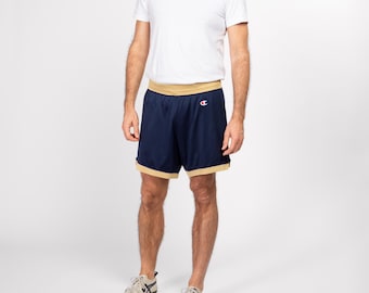 May include: Navy blue basketball shorts with a gold waistband and trim. The shorts have a small white "C" logo on the right hip.