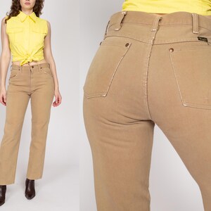 May include: A pair of light brown high-waisted jeans with a straight leg fit. The jeans have a classic five-pocket design and a button fly.