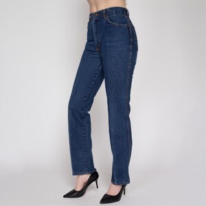 Peut inclure: Un jean en denim bleu foncé à taille haute et à jambe droite.