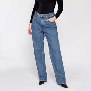 Puede incluir: Un par de pantalones vaqueros azules de mezclilla con corte recto. Los pantalones tienen cintura alta y están hechos de una tela suave y cómoda.