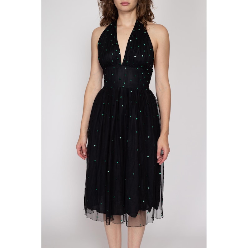 May include: A black halter dress with a green sequin pattern. The dress has a fitted bodice and a full skirt.