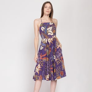 May include: A purple midi dress with a floral print. The dress has a halter neckline and a flowy skirt.