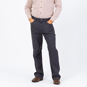 Puede incluir: Pantalones de vestir gris carbón con bolsillos delanteros. Los pantalones se combinan con una camisa abotonada con un pequeño patrón repetitivo en tonos marrones y blancos. La persona lleva zapatos de cuero marrones.